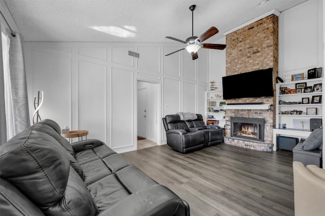 living room with built in shelves, a textured ceiling, and a fireplace