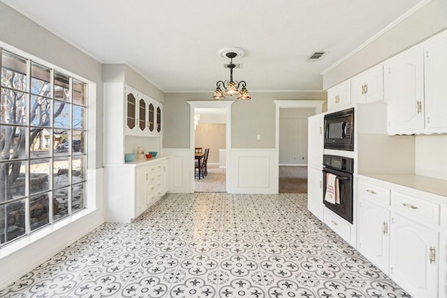 kitchen featuring decorative light fixtures, black appliances, a wealth of natural light, and crown molding