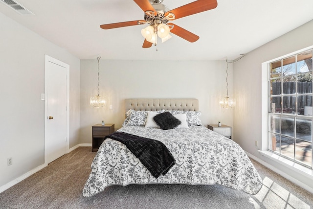 bedroom with ceiling fan with notable chandelier and carpet flooring