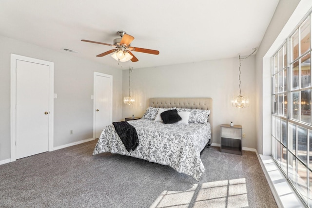 carpeted bedroom with ceiling fan with notable chandelier