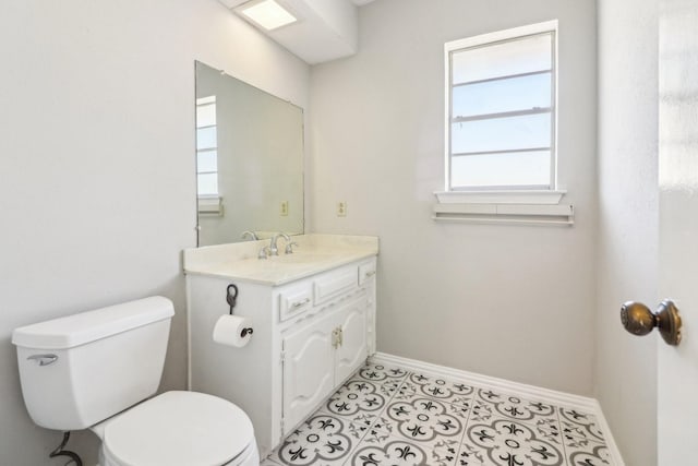 bathroom with plenty of natural light, toilet, tile patterned flooring, and vanity