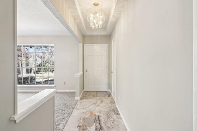 doorway to outside featuring a raised ceiling and an inviting chandelier