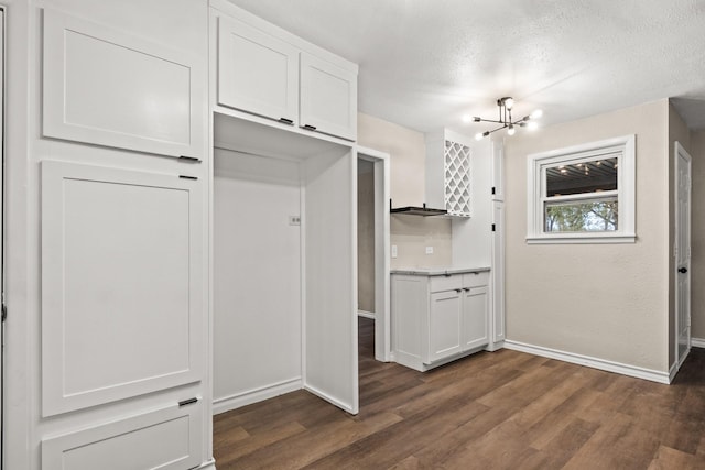 kitchen featuring a textured ceiling, a chandelier, white cabinetry, and dark hardwood / wood-style flooring