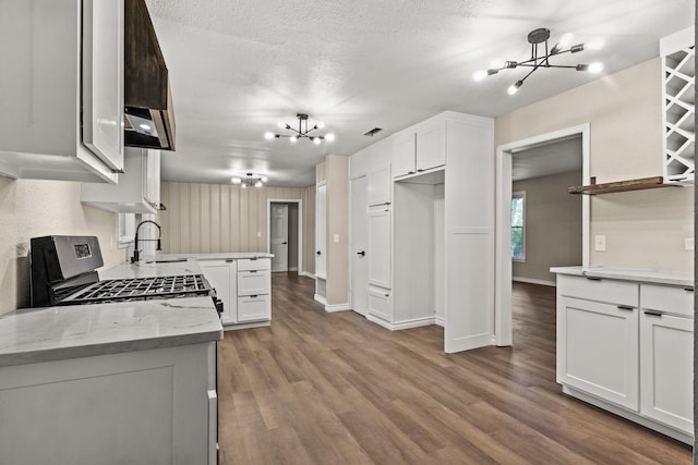 kitchen with light stone countertops, a chandelier, white cabinets, sink, and stainless steel range with gas cooktop