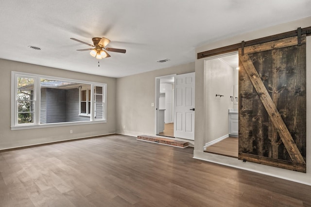 unfurnished room featuring ceiling fan, a barn door, and wood-type flooring