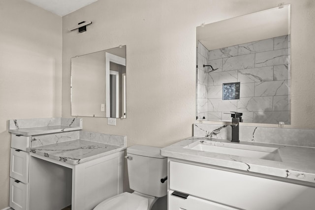 bathroom featuring a tile shower, toilet, and vanity