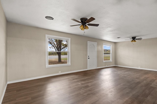 empty room with ceiling fan, plenty of natural light, and dark hardwood / wood-style flooring