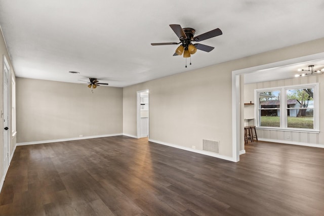 empty room featuring ceiling fan with notable chandelier and dark hardwood / wood-style flooring