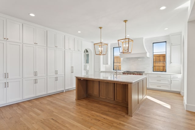 kitchen with white cabinetry and an island with sink