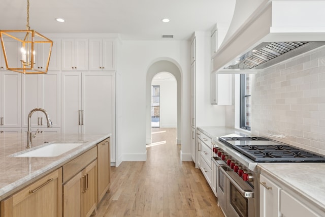 kitchen featuring light brown cabinets, sink, premium range hood, a healthy amount of sunlight, and double oven range