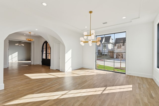 unfurnished dining area featuring light hardwood / wood-style flooring and an inviting chandelier