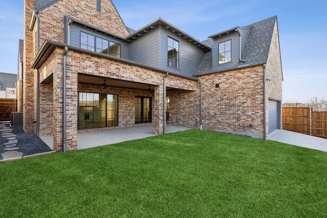 rear view of property with a patio area, a lawn, and a garage