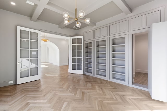 spacious closet featuring beam ceiling, french doors, and an inviting chandelier