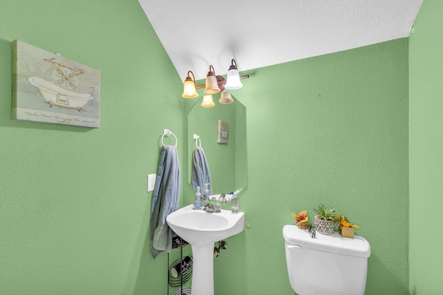 bathroom with sink, toilet, vaulted ceiling, and a textured ceiling