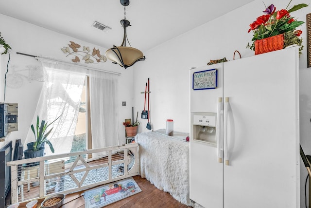 bedroom featuring white fridge with ice dispenser and hardwood / wood-style floors