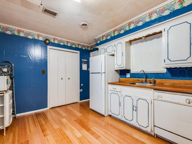 kitchen with white appliances, wood counters, white cabinetry, light hardwood / wood-style floors, and sink