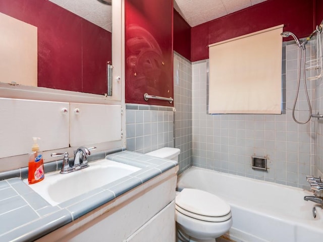 full bathroom featuring tiled shower / bath combo, toilet, vanity, and tile walls