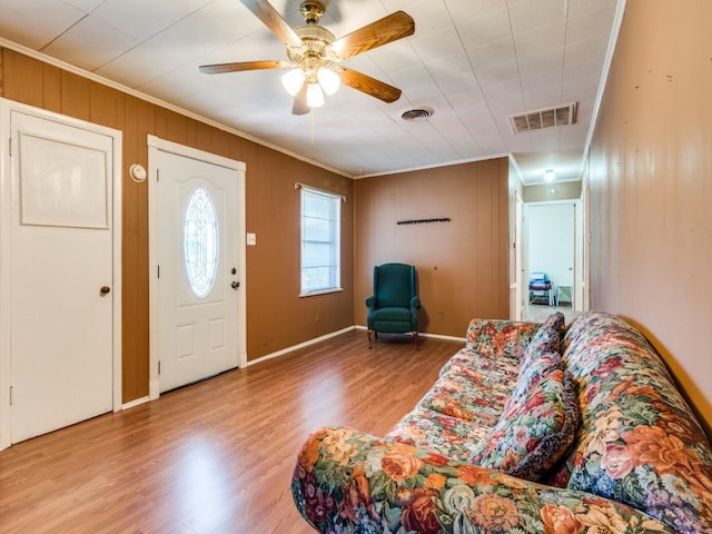 living room with light wood-type flooring, ceiling fan, and crown molding