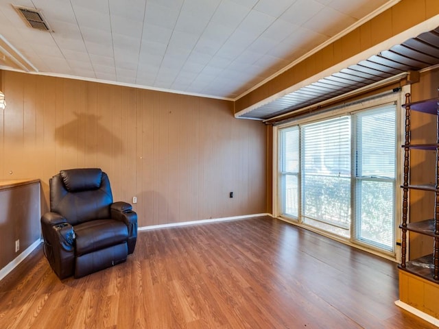 sitting room featuring crown molding, hardwood / wood-style floors, and wood walls