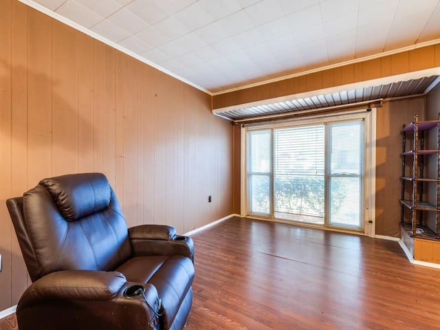 sitting room featuring hardwood / wood-style floors, crown molding, and wooden walls