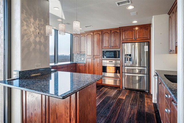 kitchen with appliances with stainless steel finishes, sink, backsplash, dark stone counters, and dark hardwood / wood-style floors