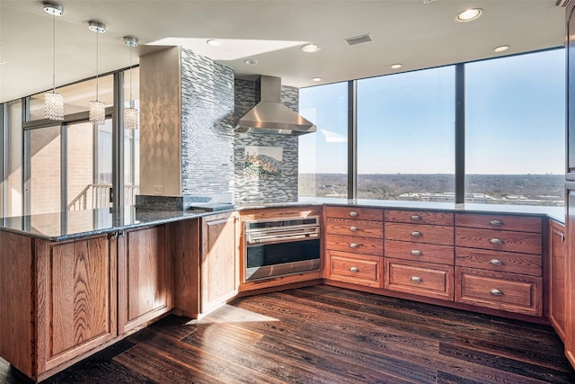 kitchen featuring stainless steel oven, range hood, dark hardwood / wood-style flooring, backsplash, and dark stone counters