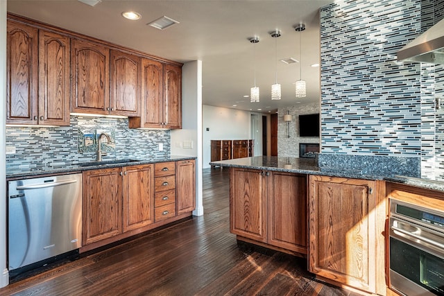 kitchen with pendant lighting, sink, backsplash, dark stone counters, and stainless steel appliances