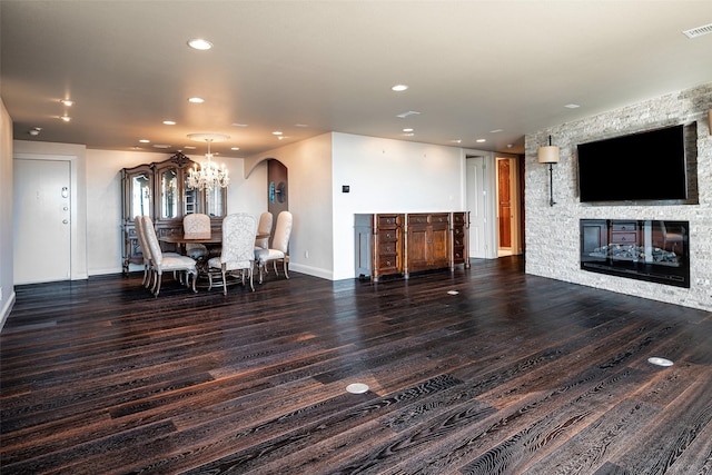 dining room with a chandelier, dark hardwood / wood-style flooring, and a stone fireplace