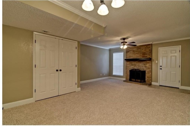 unfurnished living room with crown molding, ceiling fan, a brick fireplace, carpet floors, and a textured ceiling