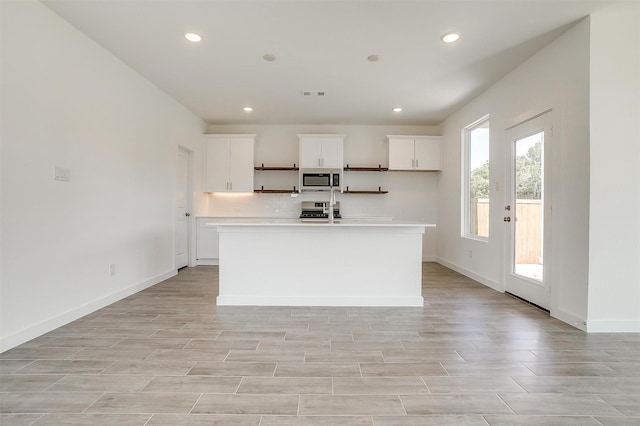 kitchen with white cabinets, a center island with sink, and appliances with stainless steel finishes