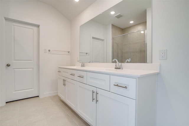 bathroom featuring vanity, vaulted ceiling, walk in shower, and tile patterned flooring