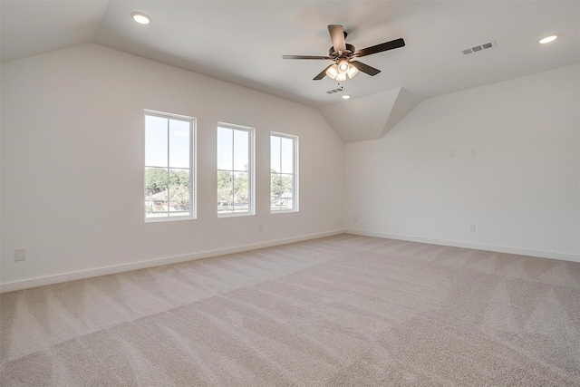 empty room featuring light carpet, vaulted ceiling, and ceiling fan