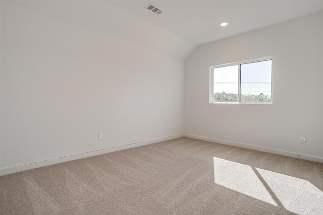 carpeted spare room featuring vaulted ceiling