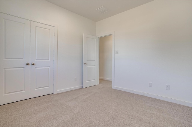 unfurnished bedroom featuring light colored carpet and a closet