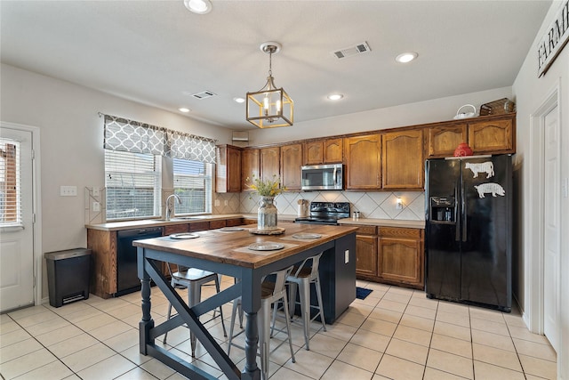 kitchen with pendant lighting, black appliances, tasteful backsplash, sink, and light tile patterned flooring