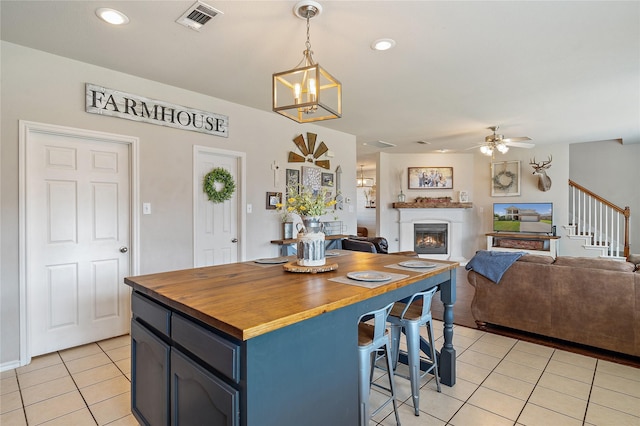 kitchen featuring wooden counters, decorative light fixtures, light tile patterned floors, blue cabinets, and a breakfast bar