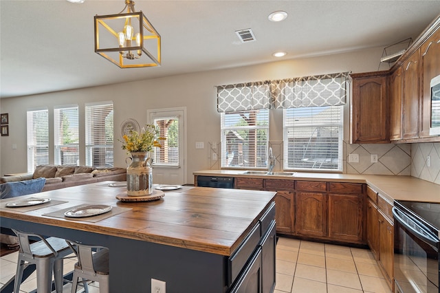 kitchen featuring pendant lighting, sink, light tile patterned flooring, black appliances, and decorative backsplash