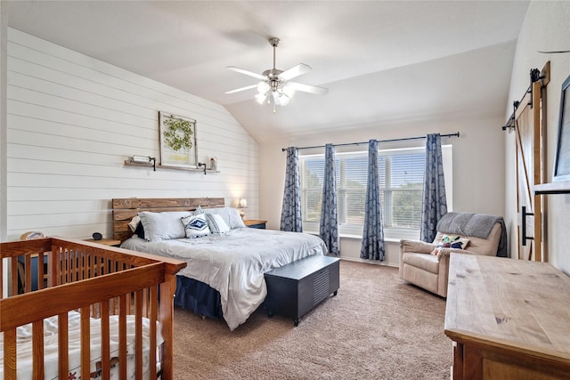 bedroom with ceiling fan, carpet, a barn door, wood walls, and lofted ceiling