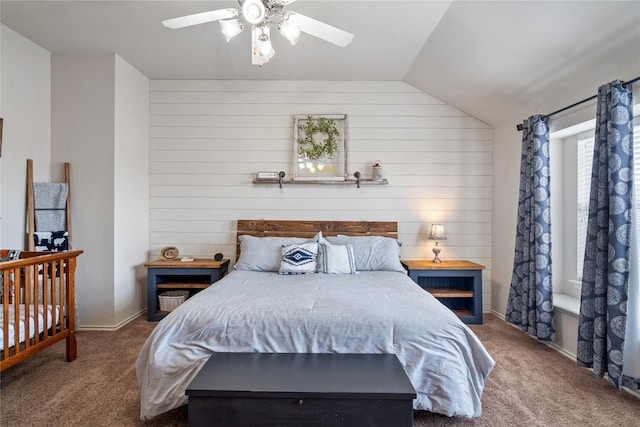 carpeted bedroom featuring ceiling fan, wooden walls, and vaulted ceiling