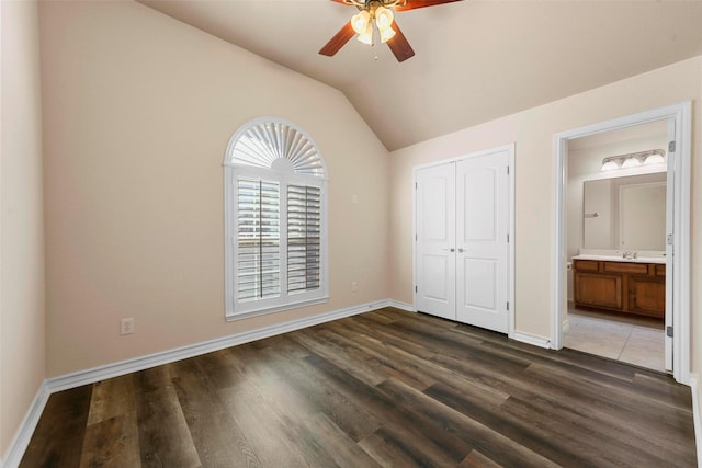 unfurnished bedroom with vaulted ceiling, a closet, ceiling fan, connected bathroom, and dark hardwood / wood-style floors