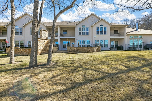 rear view of house with a balcony and a yard