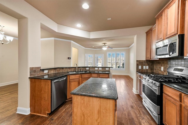 kitchen featuring a center island, stainless steel appliances, dark stone countertops, sink, and kitchen peninsula