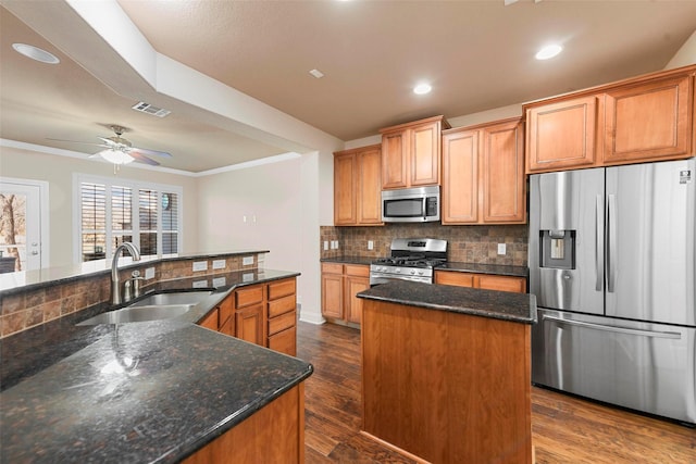 kitchen featuring appliances with stainless steel finishes, dark wood-type flooring, sink, a kitchen island with sink, and crown molding