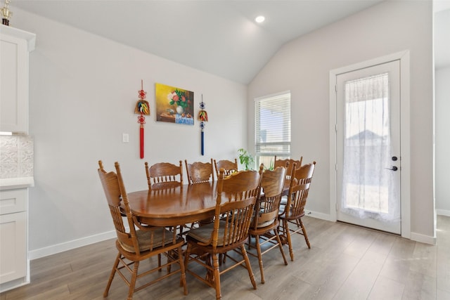 dining space featuring hardwood / wood-style floors and vaulted ceiling