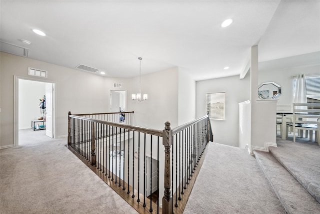 hallway with an inviting chandelier, plenty of natural light, and carpet