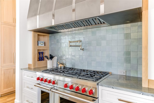 kitchen featuring wall chimney exhaust hood, tasteful backsplash, light hardwood / wood-style flooring, double oven range, and light stone countertops