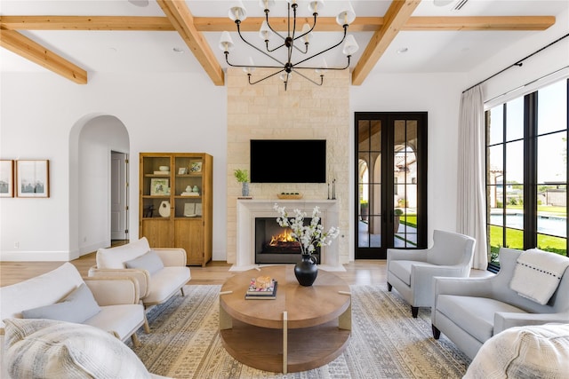 living room with light hardwood / wood-style flooring, a fireplace, french doors, and beamed ceiling