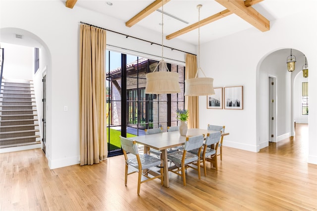 dining space with beam ceiling and light hardwood / wood-style flooring