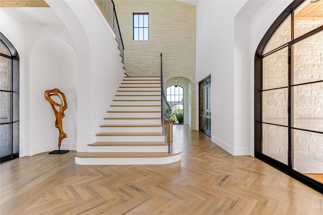 staircase featuring a high ceiling and parquet floors