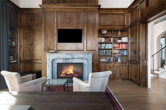 living area with a fireplace, built in features, and wood-type flooring